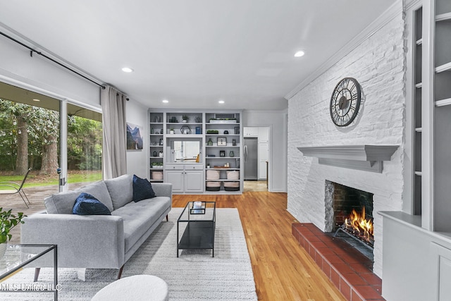 living room with built in features, ornamental molding, hardwood / wood-style flooring, and a fireplace