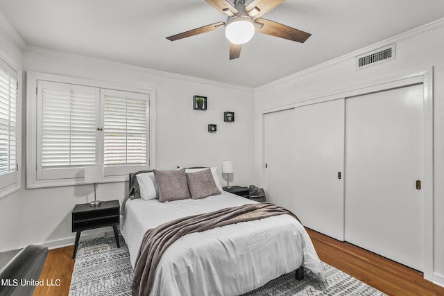 bedroom with crown molding, dark hardwood / wood-style floors, a closet, and ceiling fan