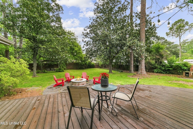 wooden deck with an outdoor fire pit and a lawn