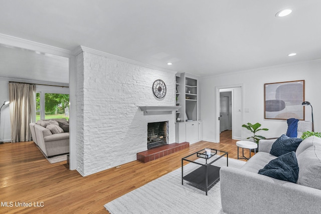 living room featuring hardwood / wood-style floors, crown molding, and a fireplace