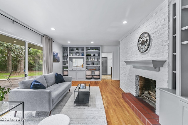 living room with crown molding, a fireplace, hardwood / wood-style flooring, and built in features