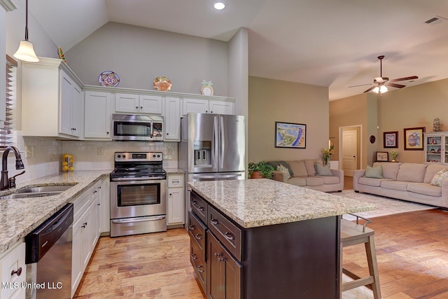 2634 Harvest Tree Dr, Southaven, MS 38672 - kitchen with appliances with stainless steel finishes, ceiling fan, backsplash, a kitchen bar, and light stone counters