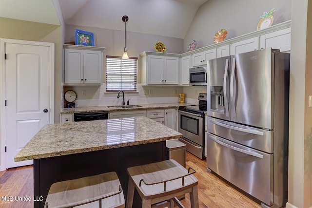 2634 Harvest Tree Dr, Southaven, MS 38672 - kitchen with appliances with stainless steel finishes, lofted ceiling, a kitchen bar, light wood-type flooring, and light stone counters