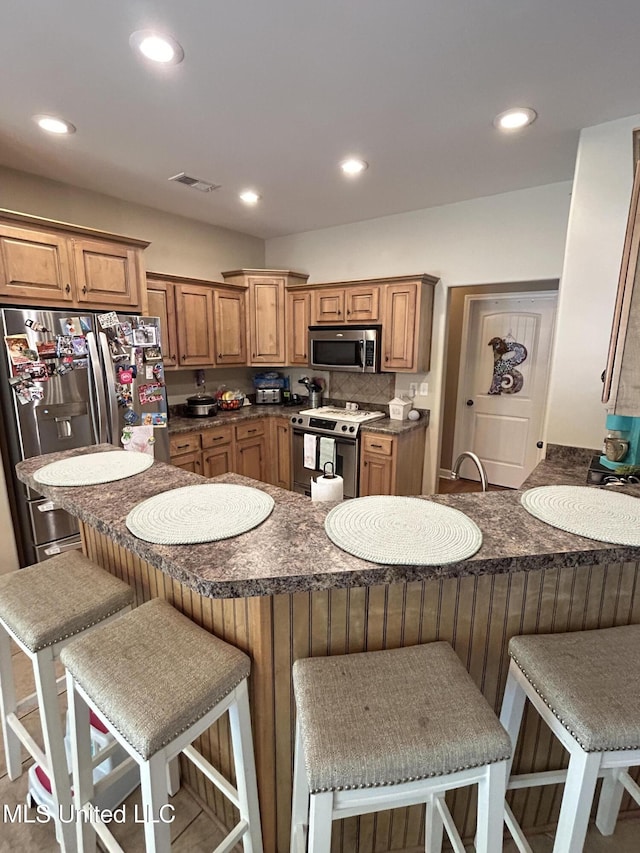 3426 Westwind Dr, Nesbit, MS 38651 - kitchen featuring appliances with stainless steel finishes, dark countertops, a peninsula, recessed lighting, and a kitchen breakfast bar