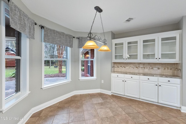 unfurnished dining area featuring light tile patterned floors, visible vents, and baseboards