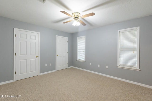 carpeted empty room with a ceiling fan and baseboards