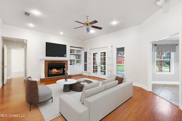 living room with visible vents, wood finished floors, a fireplace, and ornamental molding