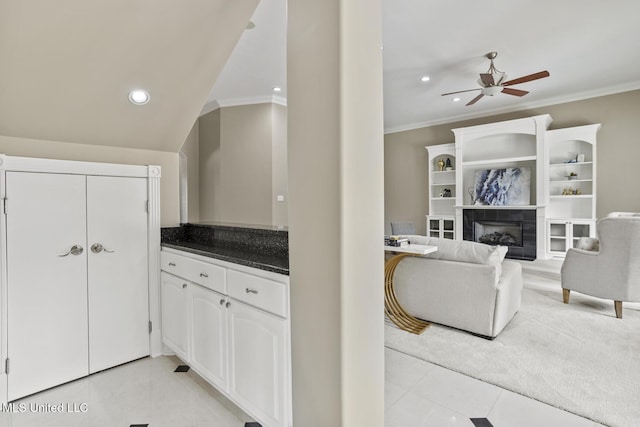 kitchen featuring light tile patterned flooring, ornamental molding, white cabinets, and a fireplace