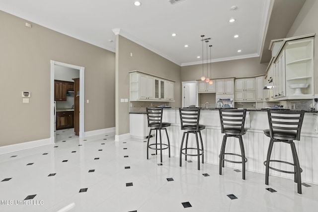 kitchen with light tile patterned floors, decorative light fixtures, ornamental molding, and a kitchen breakfast bar