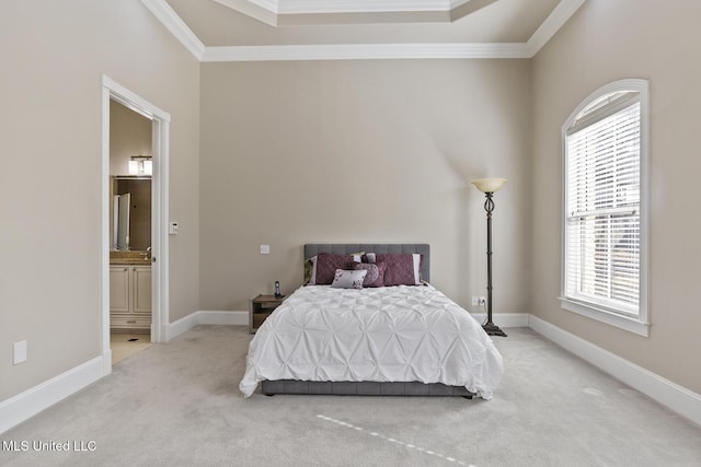 bedroom featuring a tray ceiling, crown molding, carpet floors, and ensuite bathroom