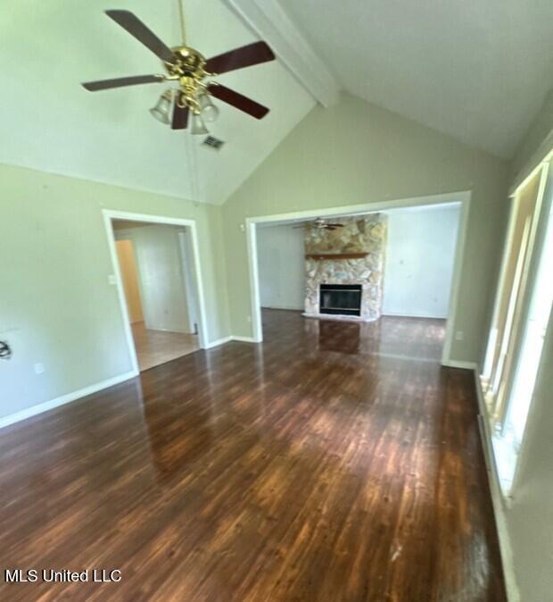 5 Union Church Rd, Tylertown, MS 39667 - unfurnished living room with wood finished floors, beam ceiling, a ceiling fan, high vaulted ceiling, and a stone fireplace