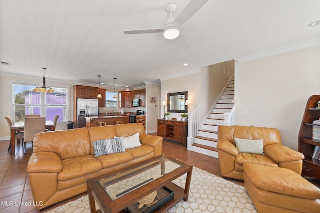 living room with light tile patterned floors, ceiling fan with notable chandelier, and crown molding