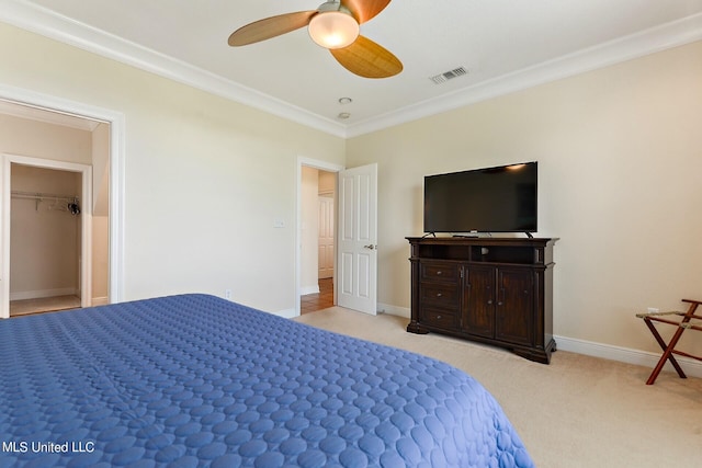 carpeted bedroom with ceiling fan, a spacious closet, and crown molding