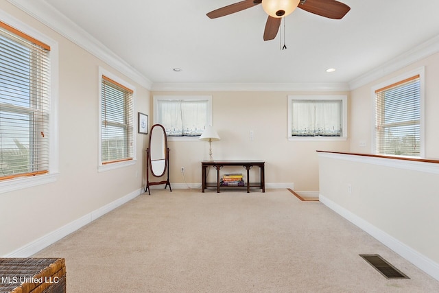 interior space featuring ceiling fan, crown molding, and light colored carpet