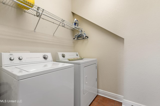 clothes washing area with dark tile patterned flooring and washing machine and clothes dryer