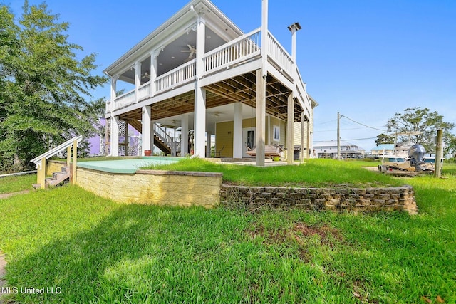 rear view of house featuring ceiling fan, a wooden deck, a lawn, and a patio