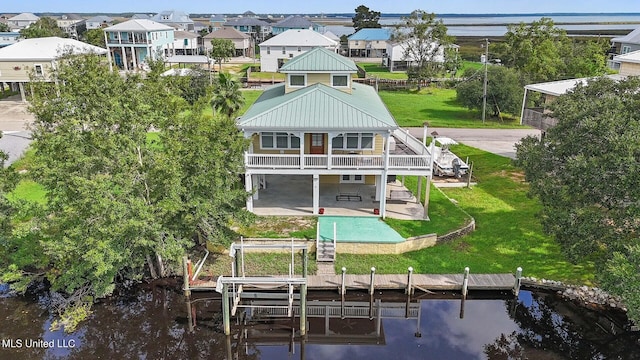 back of house with a balcony, a patio area, a water view, and a yard