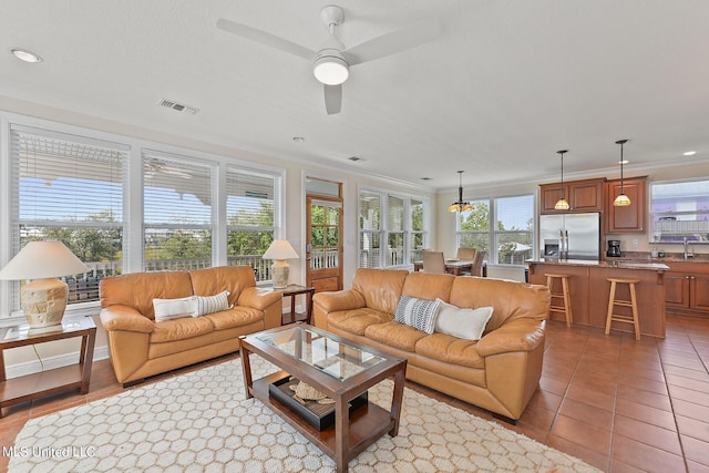 living room with a wealth of natural light, ornamental molding, and light tile patterned flooring