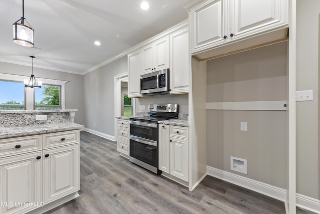 kitchen with hanging light fixtures, appliances with stainless steel finishes, white cabinets, hardwood / wood-style flooring, and light stone counters