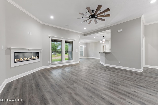 unfurnished living room with ceiling fan with notable chandelier, dark wood-type flooring, and crown molding