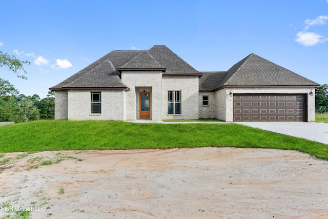 french country home featuring a garage and a front lawn