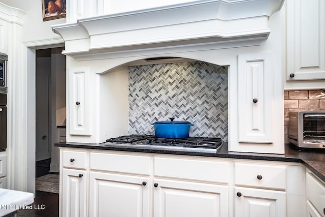 kitchen with white cabinets, appliances with stainless steel finishes, dark hardwood / wood-style floors, and backsplash