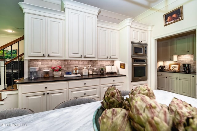 kitchen with stainless steel appliances, dark stone counters, decorative backsplash, and white cabinets