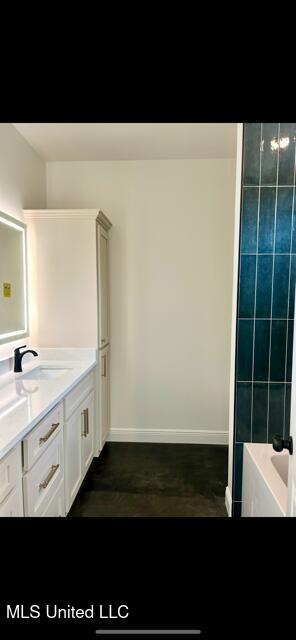 bathroom featuring vanity, baseboards, walk in shower, a bath, and concrete floors