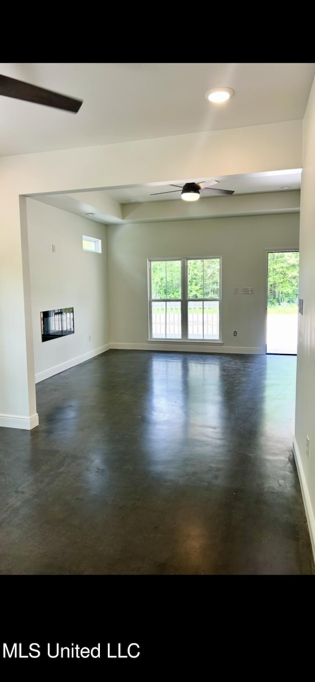 unfurnished room with ceiling fan, concrete floors, and a wealth of natural light