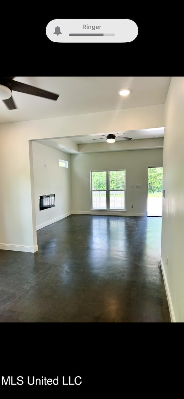 interior space with finished concrete floors, a ceiling fan, and baseboards