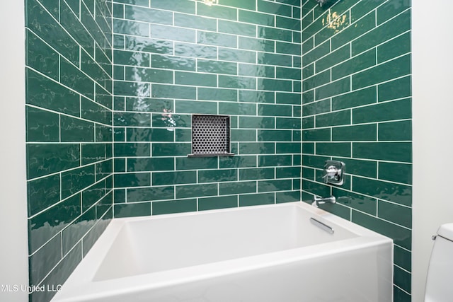 bathroom featuring tiled shower / bath and toilet