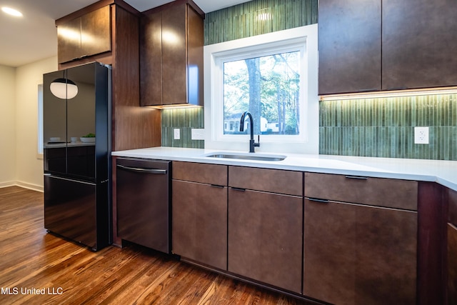 kitchen featuring sink, black fridge, stainless steel dishwasher, dark hardwood / wood-style floors, and dark brown cabinets