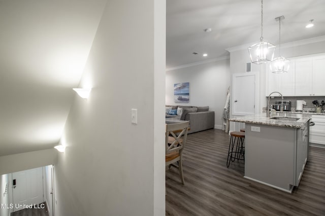 kitchen featuring sink, an island with sink, dark hardwood / wood-style flooring, white cabinetry, and a breakfast bar