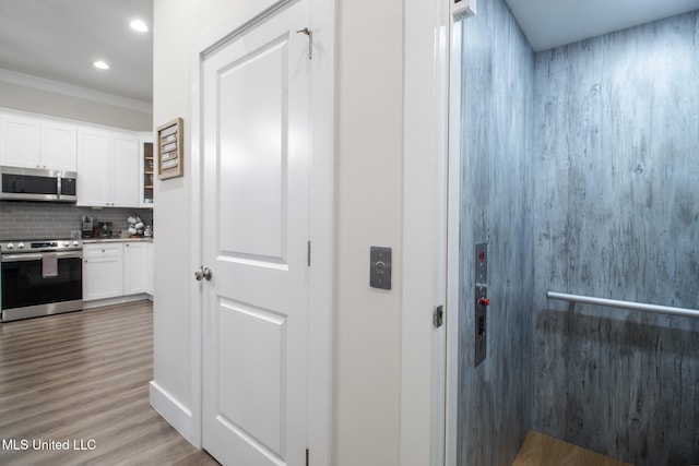 corridor with crown molding, hardwood / wood-style flooring, and elevator