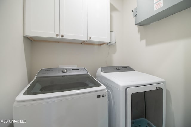 clothes washing area featuring washer and dryer and cabinets