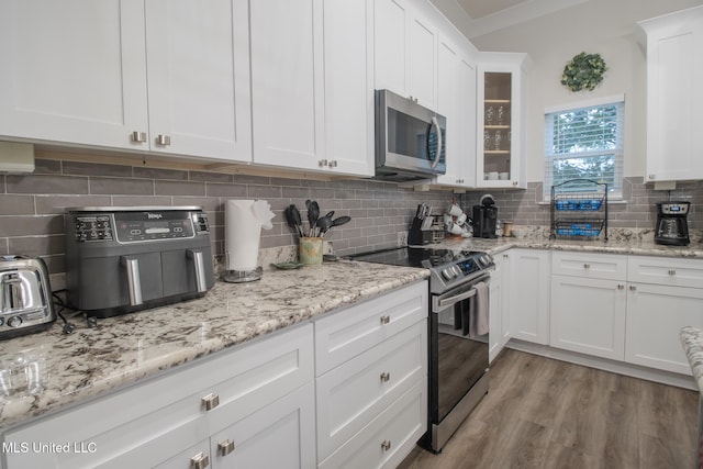 kitchen featuring white cabinetry, stainless steel appliances, backsplash, and light hardwood / wood-style floors