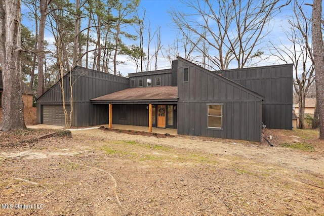 rear view of house with a shingled roof, board and batten siding, and an attached garage