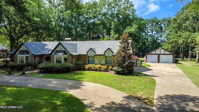 tudor home featuring an outdoor structure, a garage, and a front lawn