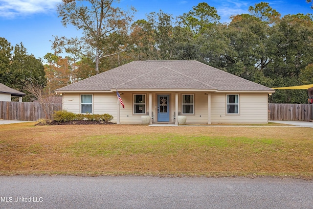 ranch-style house featuring roof with shingles, fence, and a front lawn