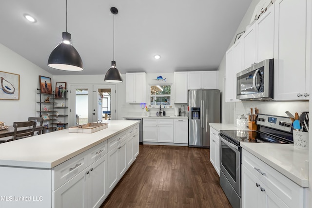 kitchen featuring white cabinets, decorative light fixtures, stainless steel appliances, light countertops, and a sink