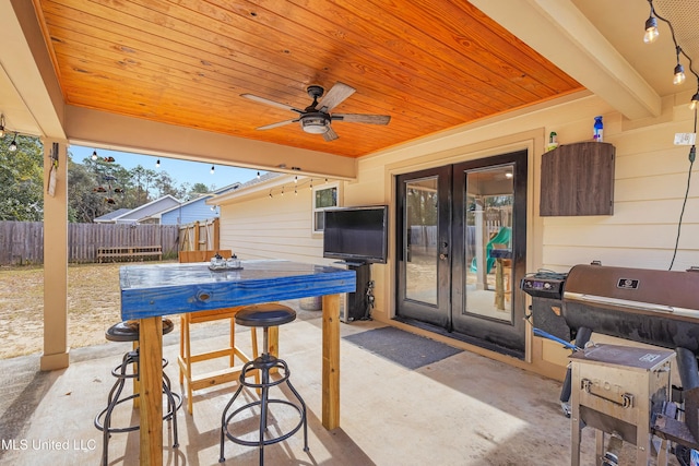 view of patio featuring ceiling fan, exterior bar, area for grilling, fence, and french doors