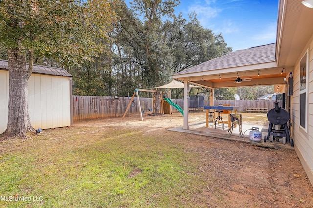 view of yard with an outbuilding, a playground, a patio, a storage shed, and a fenced backyard