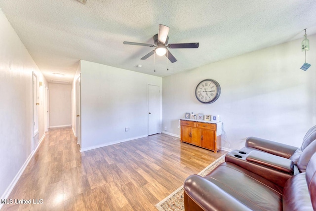 living area featuring ceiling fan, a textured ceiling, and light wood-type flooring