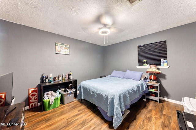 bedroom with ceiling fan, wood-type flooring, and a textured ceiling