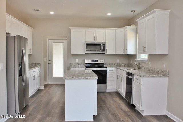 kitchen with white cabinets, appliances with stainless steel finishes, sink, and a center island