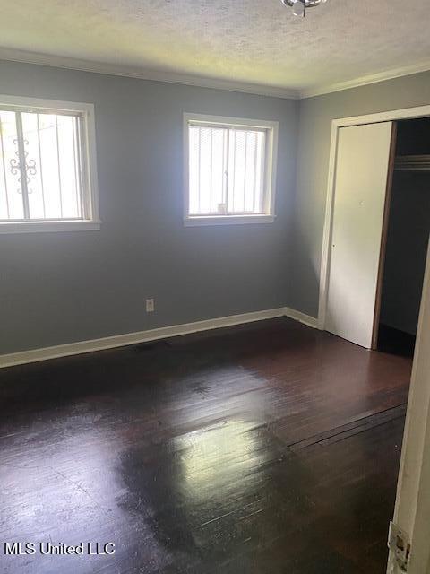 2804 Revere St, Jackson, MS 39212 - unfurnished bedroom featuring ornamental molding, baseboards, dark wood-style flooring, a closet, and a textured ceiling