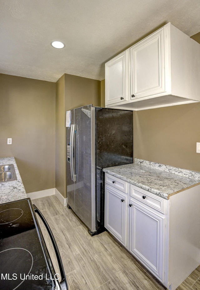 223 Second Ave, Vicksburg, MS 39183 - kitchen with light stone countertops, stainless steel refrigerator with ice dispenser, light wood-type flooring, sink, and white cabinets