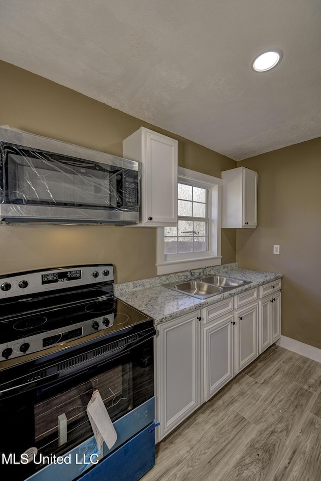 223 Second Ave, Vicksburg, MS 39183 - kitchen with light stone countertops, sink, electric range, light hardwood / wood-style flooring, and white cabinets