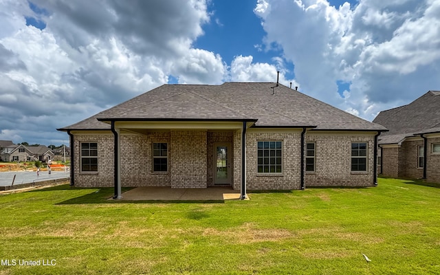 1716 Ryker Rd, Southaven, MS 38672 - rear view of house with a patio, a lawn, a shingled roof, and brick siding