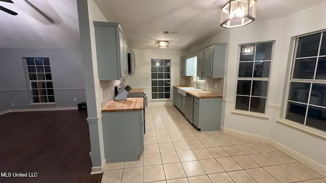 kitchen with sink, light tile patterned floors, butcher block counters, gray cabinetry, and stainless steel appliances